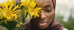 Close up portrait of muslim woman covering half of face with a yellow flowers