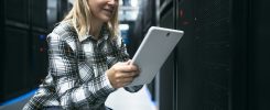 Female data center technician working inside server rack room