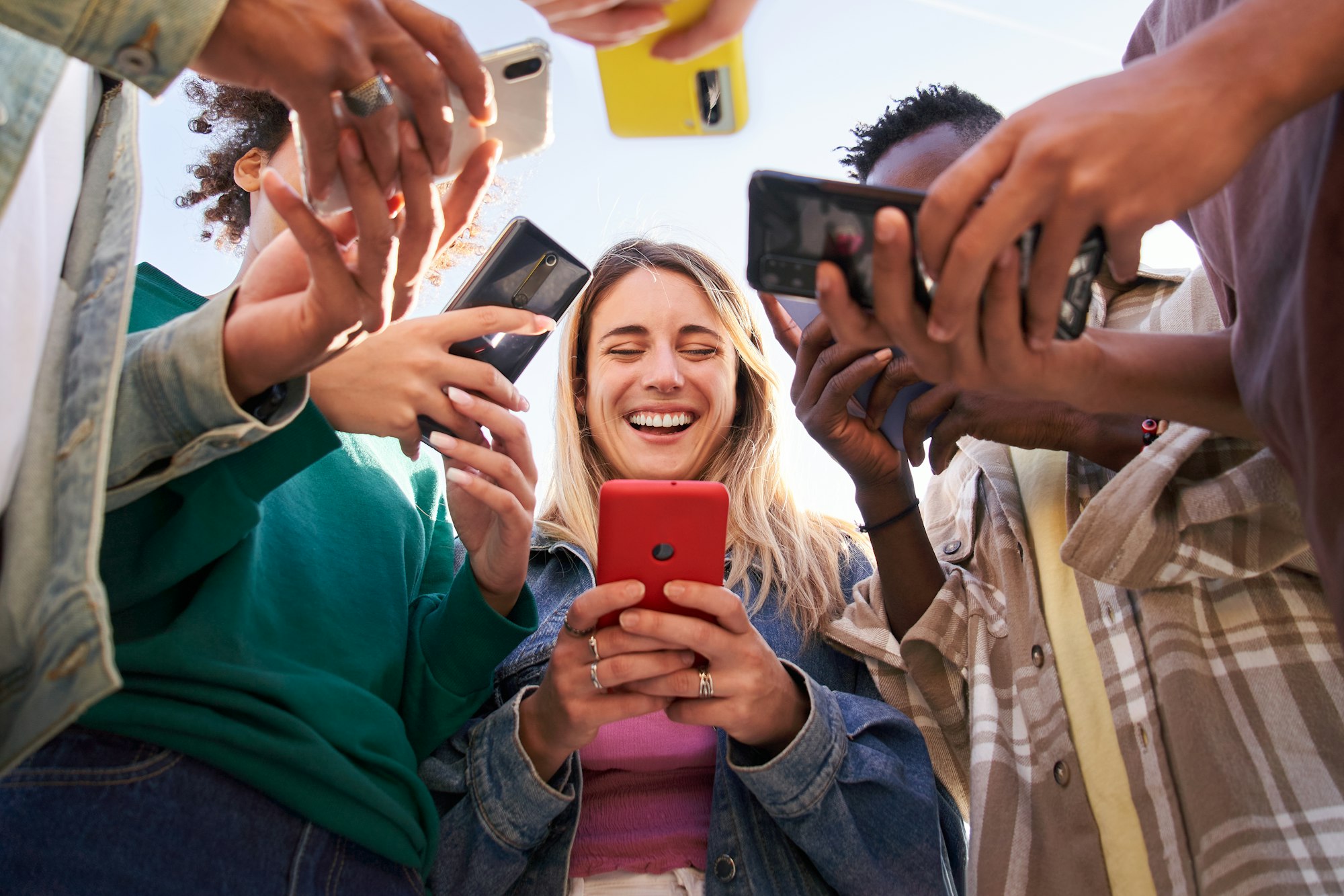 Low angle view of a group of young teenagers using cell phones. Concept of technology, connection.
