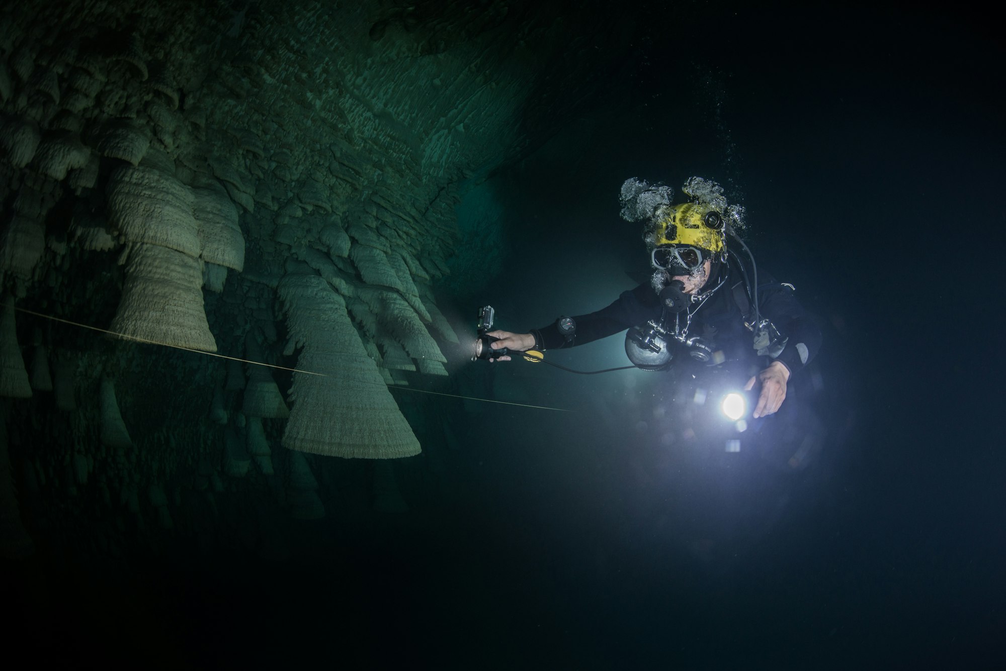 Scuba diver exploring unique natural formations known as "bells" in submerged caves beneath the